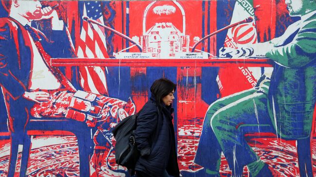 Женщина проходит мимо граффити в Тегеране, Иран
