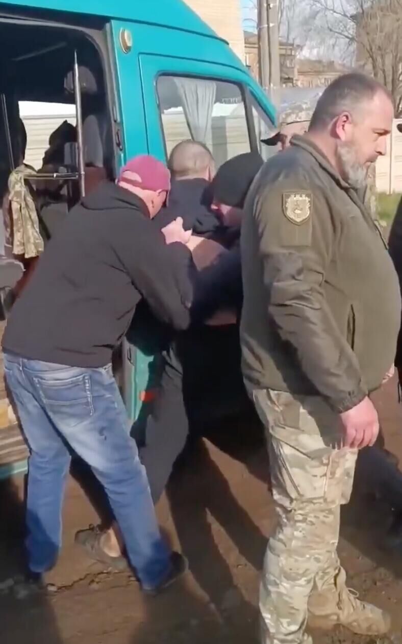 Сотрудники ТЦК Украины заталкивают мужчину в автобус. Кадр видео - РИА Новости, 1920, 16.04.2025