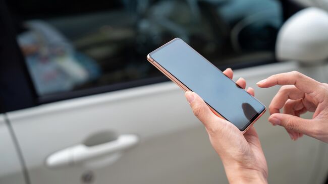 Девушка использует смартфон, чтобы открыть двери автомобиля