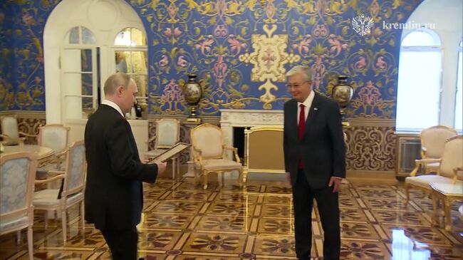 Путин вручает Токаеву наградной лист на присвоение его отцу звания Героя Советского Союза