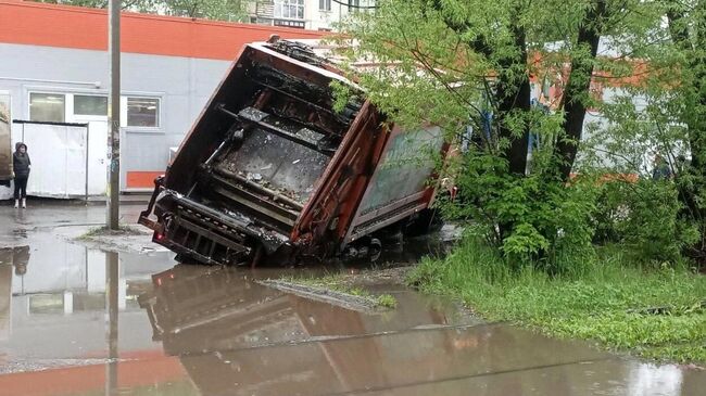 Мусоровоз провалился в яму после дождя в Омске