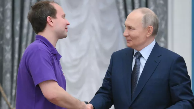 Президент РФ Владимир Путин и победитель национальной премии Россия – страна возможностей в номинации Инклюзия в 2024 г., президент ассоциации инклюзивных медиапроектов Жизнь в темноте Иван Ерхов. 27 мая 2025