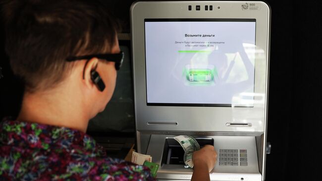 Мужчина снимает наличные в банкомате