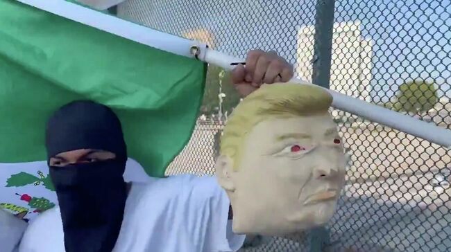 Протестующий машет самодельной головой Трампа 