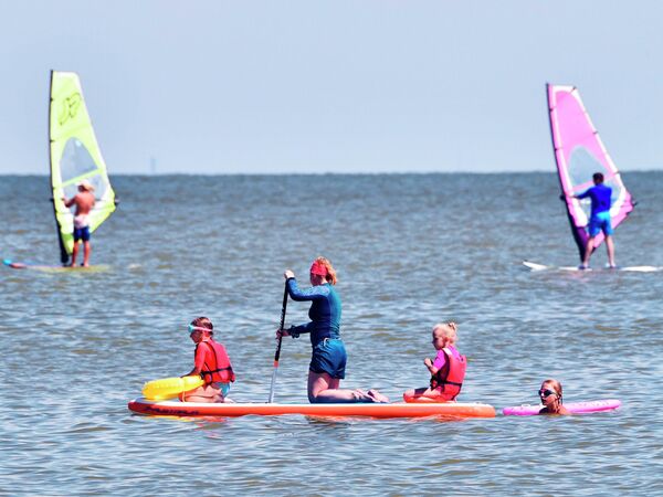 Женщина с детьми на сап-борде в Таганрогском заливе Азовского моря в курортном городе Ейск Женщина с детьми на сап-борде в Таганрогском заливе Азовского моря в курортном городе Ейск