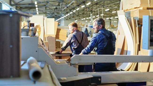 Рабочие во время работы на заводе по производству мебели