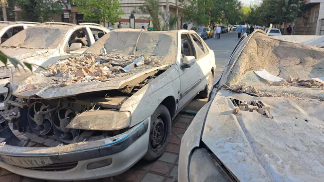 Поврежденные автомобили на площади в районе Нармак в Тегеране после израильских авиаударов