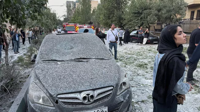 Люди осматривают последствия массированного израильского авиаудара в Тегеране
