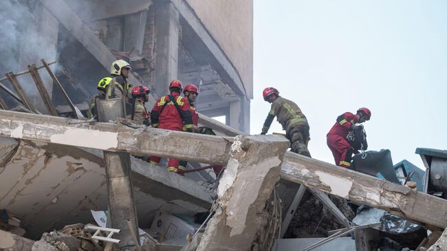 Иранские спасатели работают на месте разрушенного жилого здания в результате израильских атак в Тегеране, Иран
