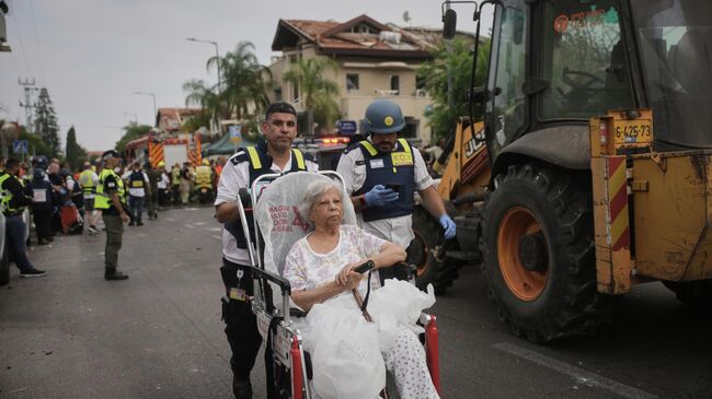 Парамедики эвакуируют женщину с места, куда попала ракета, выпущенная из Ирана, в Ришон-ле-Ционе, Израиль
