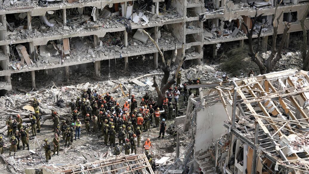 © AP Photo / Oded Balilty<br>Спасатели, военные и пожарные на месте ракетного удара Ирана в Тель-Авиве, Израиль