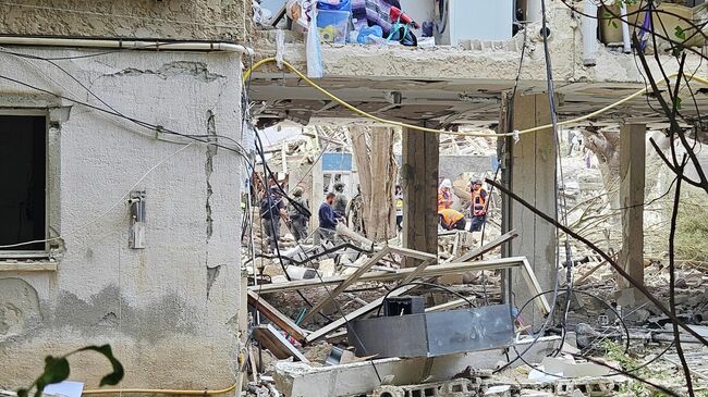 Сотрудники спасательной службы разбирают завалы жилого дома на одной из улиц Тель-Авива, частично разрушенного в результате ракетной атаки Ирана