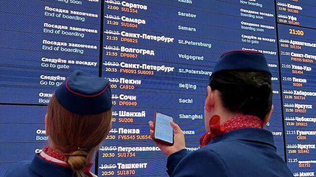 Сотрудницы авиакомпании у табло вылета в аэропорту Шереметьево в Москве