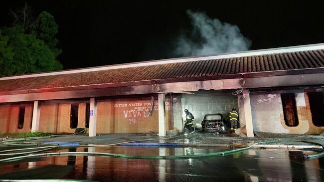 Пожарные ликвидируют огонь после столкновения автомобиля с отделением почты в Сан-Хосе, Калифорния