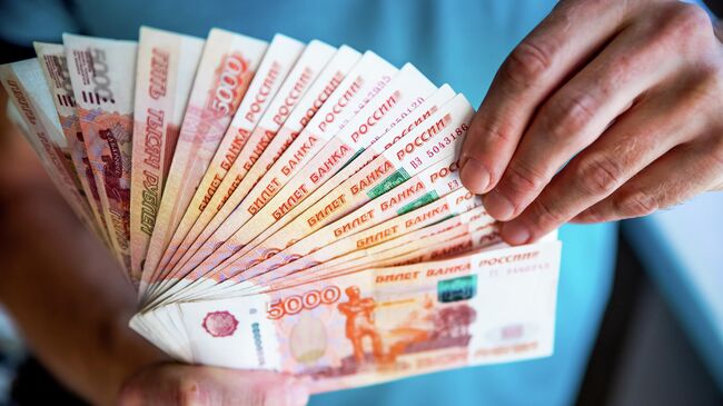 Мужчина держит в руках российские рубли