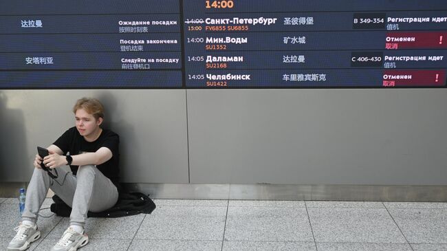 Молодой человек у табло вылета в Международном аэропорту Шереметьево имени А.С. Пушкина