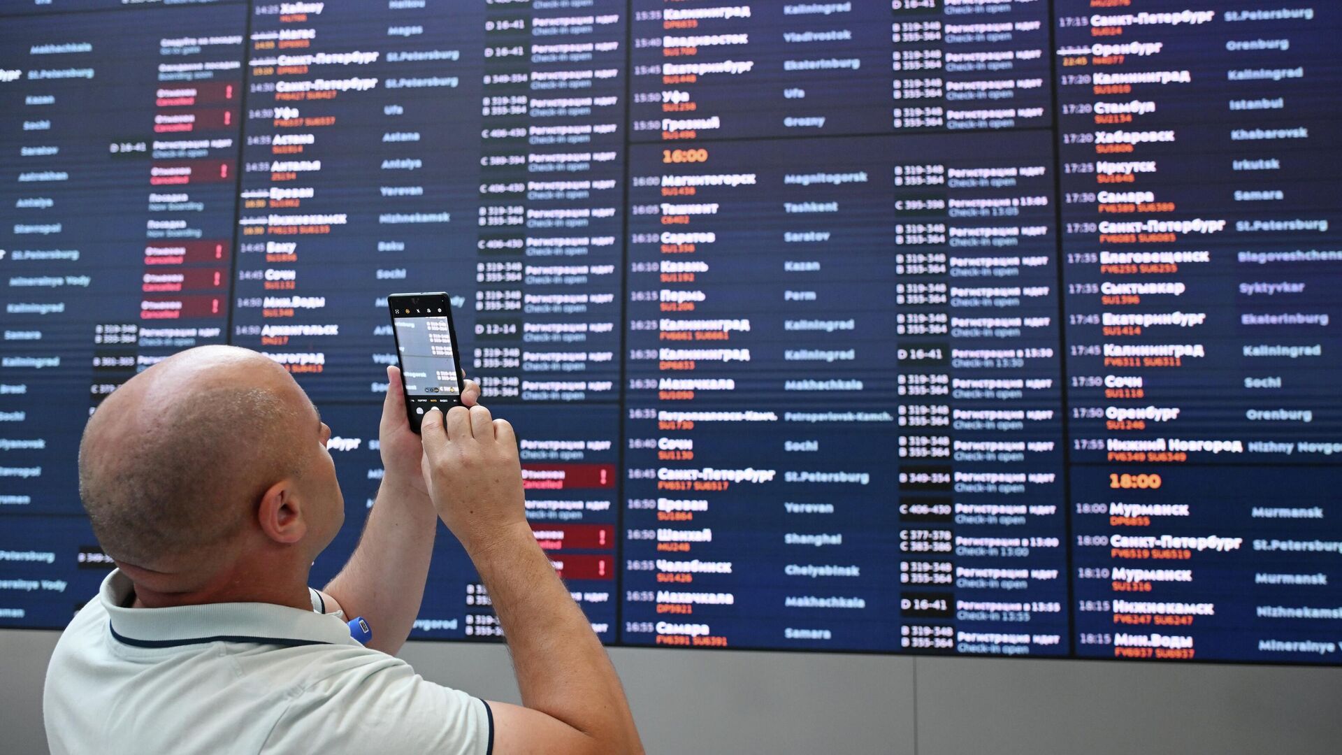 Мужчина фотографирует табло вылета в Международном аэропорту Шереметьево имени А.С. Пушкина - РИА Новости, 1920, 12.12.2025