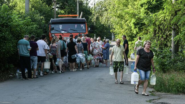 Местные жители стоят в очереди за водой в пункте временного подвоза в Кировском районе Донецка