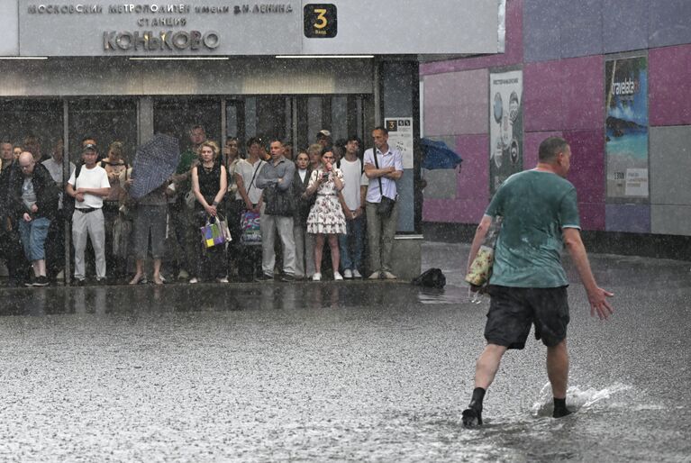 Люди у вестибюля станции московского метрополитена Коньково во время дождя Люди у вестибюля станции московского метрополитена Коньково во время дождя