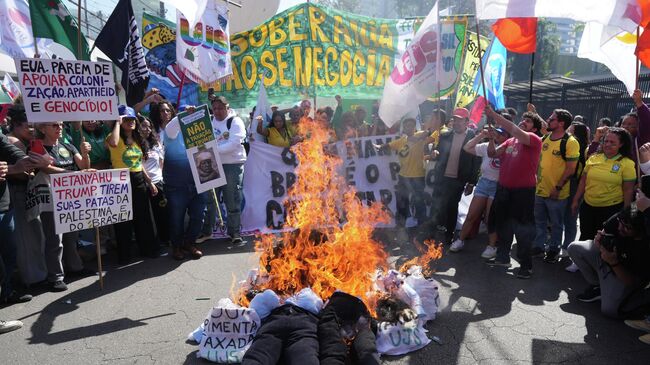 Протестующие в Сан-Паулу сжигают чучела президента США Дональда Трампа и бывшего президента Бразилии Жаира Болсонару в знак протеста против 50-процентных пошлин США на бразильские товары