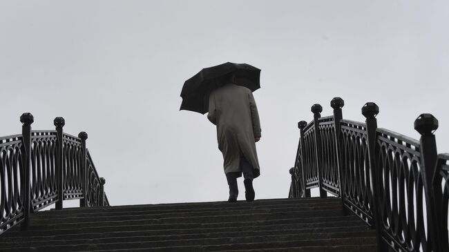 Прохожий на Садовническом мосту во время дождя в Москве