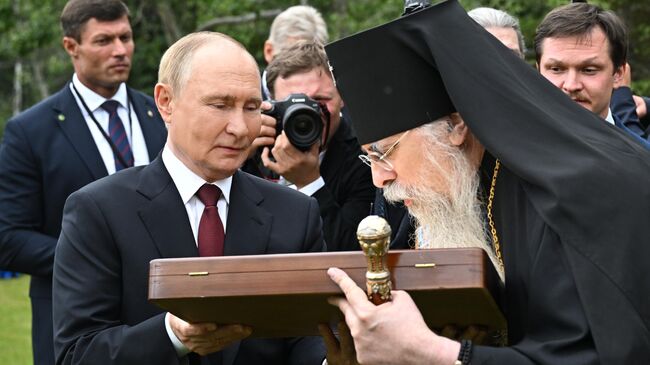 Президент РФ Владимир Путин и архиепископ Ситкинский и Аляскинский Алексий после возложения цветов к могилам советских воинов на мемориальном кладбище Форт Ричардсон на Аляске Президент РФ Владимир Путин и архиепископ Ситкинский и Аляскинский Алексий после возложения цветов к могилам советских воинов на мемориальном кладбище Форт Ричардсон на Аляске