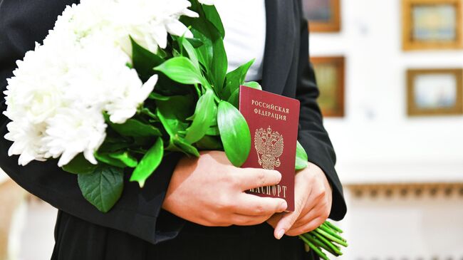 Юным житель Химок держит в руках букет и паспорт 
