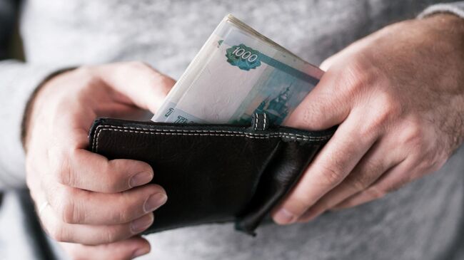 Мужчина достает деньги из кошелька