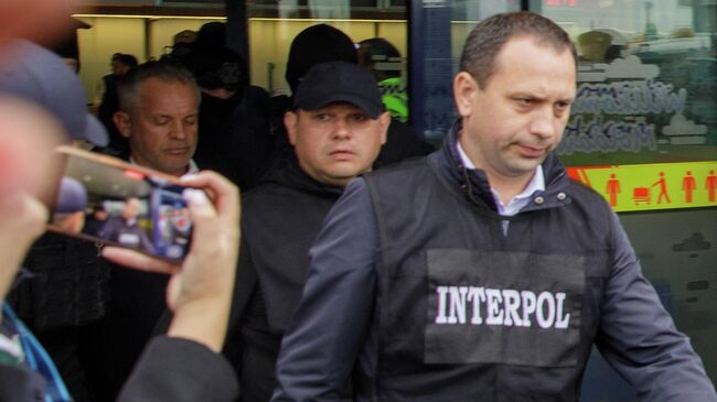 Сотрудники полиции сопровожают олигарха Владимира Плахотнюка в аэропорту в Кишиневе