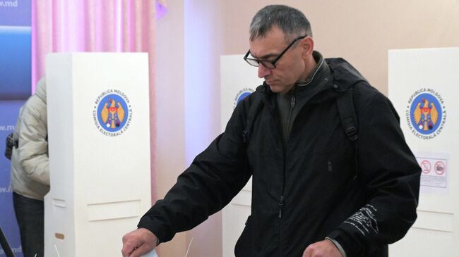 Мужчина голосует на избирательном участке в посольстве Республики Молдавия в Москве на парламентских выборах
