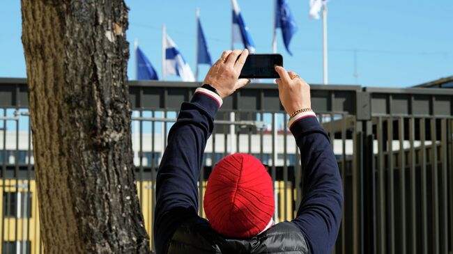 Мужчина фотографирует флаги НАТО и Финляндии