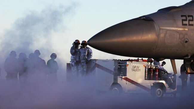 Летный состав рядом с американским истребителем F/A-18E Super Hornet на борту авианосца USS Nimitz