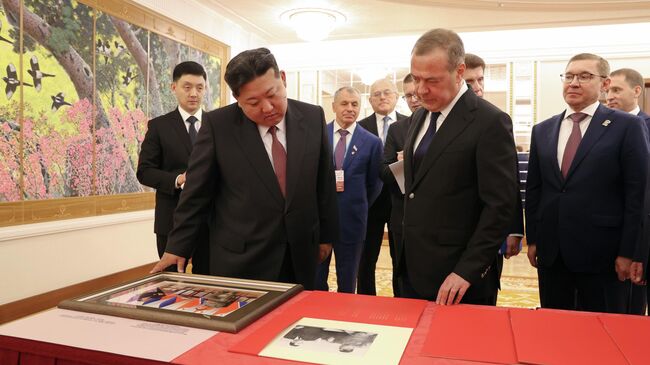 Заместитель председателя Совета безопасности РФ Дмитрий Медведев и председатель государственных дел КНДР Ким Чен Ын рассматривают архивные фотографии и документы во время встречи в Пхеньяне