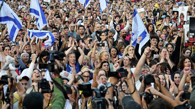 Люди смотрят прямую трансляцию освобождения заложников из сектора Газа в Тель-Авиве, Израиль. 13 октября 2025