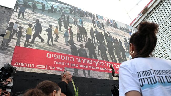 Люди смотрят прямую трансляцию освобождения заложников из сектора Газа в Тель-Авиве, Израиль. 13 октября 2025 года