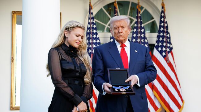 Президент США Дональд Трамп вручает президентскую медаль вдове активиста Чарли Кирка Эрике Кирк. 14 октября 2025