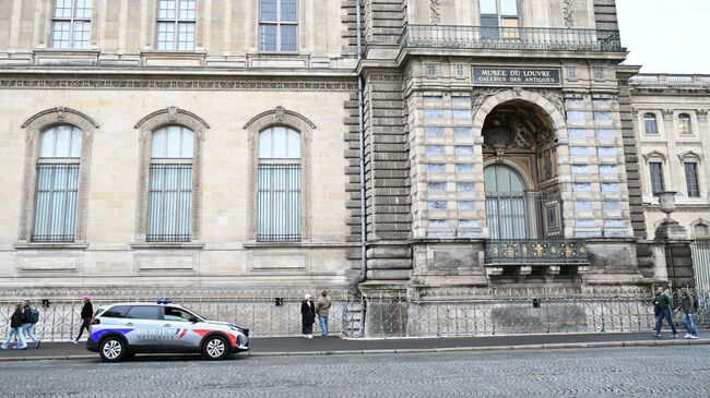 Полицейская машина у здания Лувра в Париже, Франция