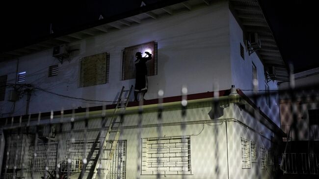 Мужчина заколачивает окна отеля, готовясь к урагану Мелисса на Ямайке