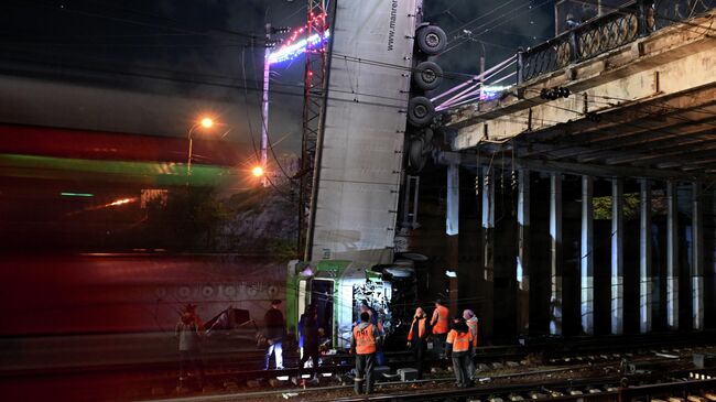 Сотрудники коммунальных служб работают на месте падения грузового автомобиля в Симферополе