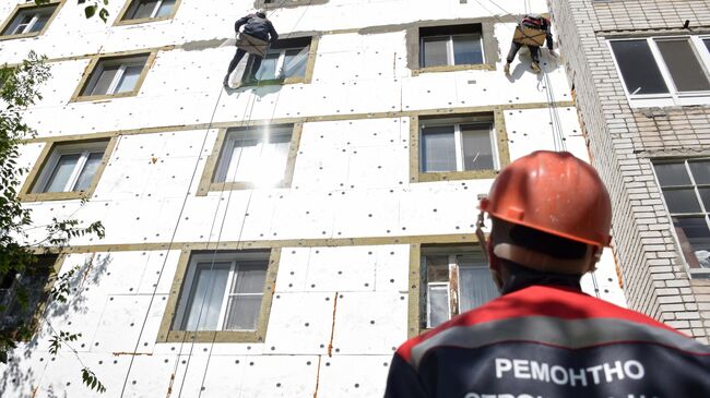 Рабочие шпаклюют фасад дома