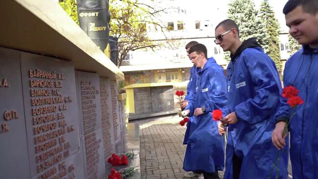 Активисты Молодой гвардии ДНР возлагают цветы к мемориалу погибшим фронтовикам-журналистам в Донецке. Кадр видео 