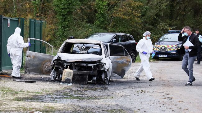 Следователи осматривают сгоревший автомобиль после того, как водитель совершившил намеренный наезд на людей на острове Олерон 