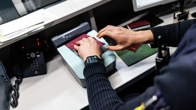 Сотрудник пограничной полиции проверяет паспорт в аэропорту Мемминген