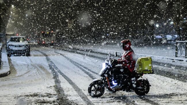 Курьер едет на электроскутере в Санкт-Петербурге