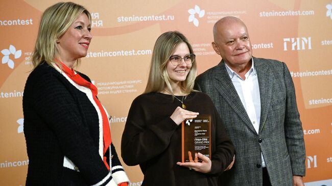 Официальный представитель Министерства иностранных дел России Мария Захарова, фотограф Екатерина Якель, получившая Гран-при за серию фотографий Русский характер: бег с препятствиями, и генеральный директор Международной медиагруппы Россия сегодня Дмитрий Киселев на церемонии награждения победителей XI Международного конкурса фотожурналистики имени Андрея Стенина. 18 ноября 2025