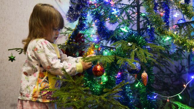 Девочка наряжает новогоднюю ель