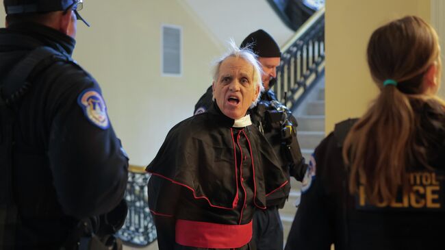 Протестующий в рясе священника задержан после попытки срыва слушаний комитета по внутренней безопасности палаты представителей конгресса США в Вашингтоне