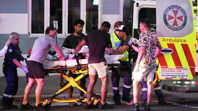 Сотрудники экстренных служб транспортируют раненного во время стрельбы на пляже Бондай в Сиднее