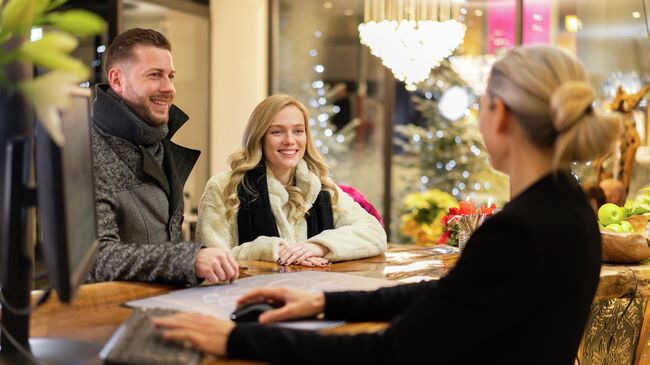 Туристы на стойке ресепшена в отеле Туристы на стойке ресепшена в отеле
