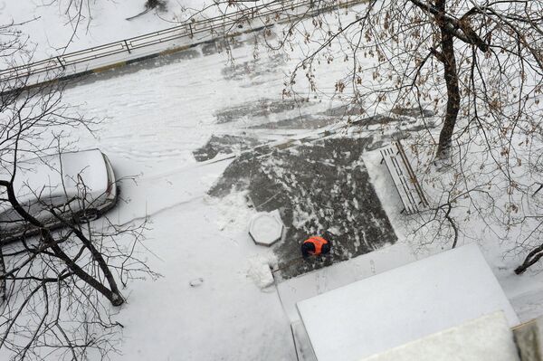 Работник коммунальных служб расчищает снег во время снегопада в Москве